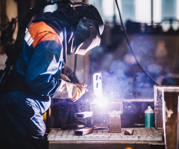 Worker welding in oxygen mask in a factory